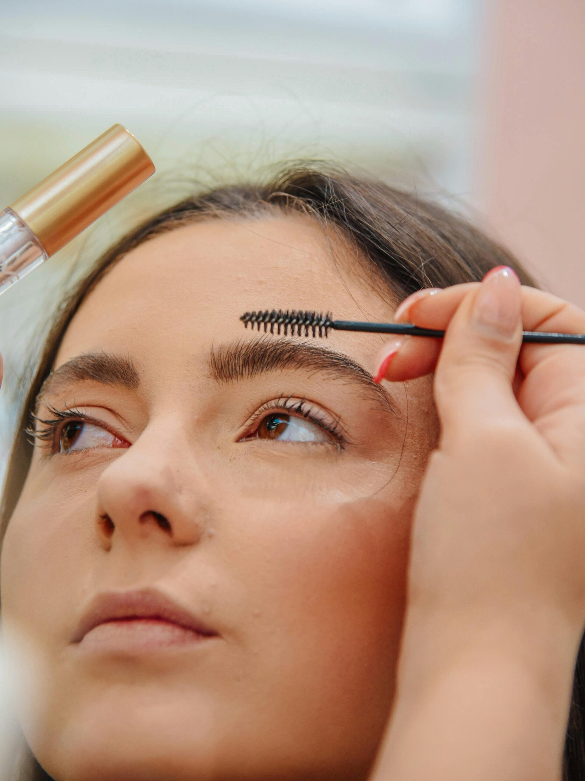 Services Makeup artist applying eyebrow gel to a young woman
