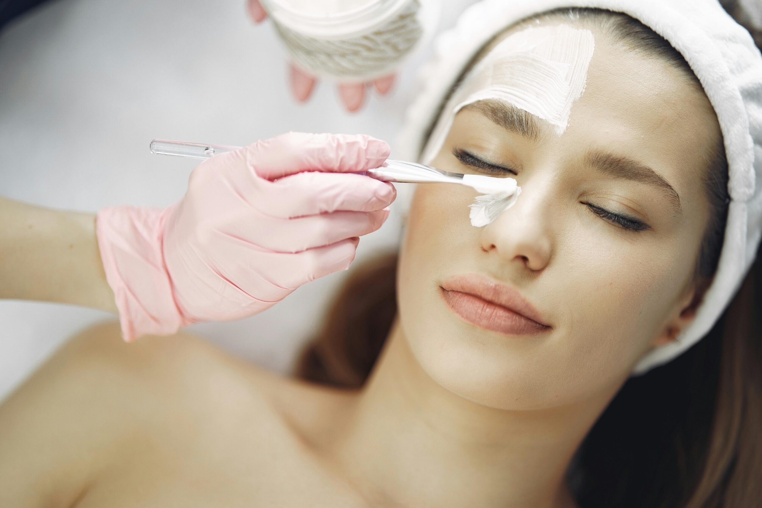 Services Close-up of a woman receiving a relaxing facial treatment with a skincare mask indoors.
